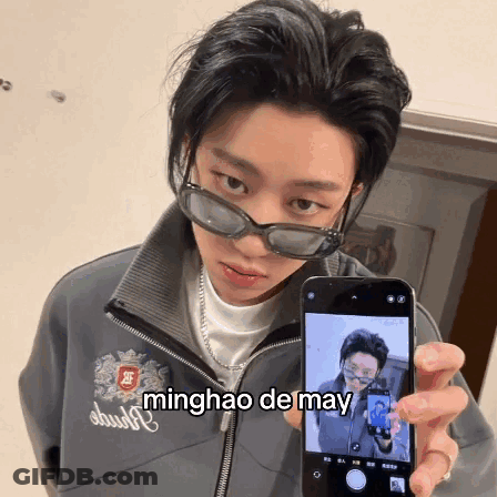 A Person Wearing Sunglasses Is Holding Up A Cell Phone With The Name Minghao De May Written On The Screen GIF