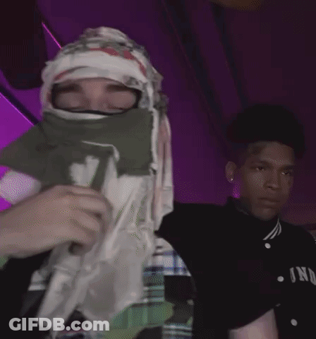 A Person With A Bandana On Their Face Is Holding A Cup With The Letter D On It GIF