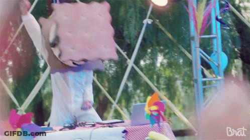 A Person With A Cookie On Their Head And The Word Brat On The Bottom Right GIF