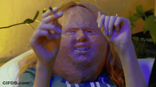 A Person With A Mask On Their Face Is Holding A Cigarette GIF