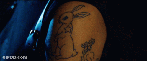 A Person With A Tattoo Of A Rabbit And Flowers On Their Arm GIF