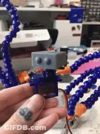 A Person With A Tattoo On Their Finger Is Holding A Robot GIF