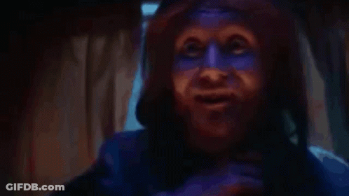A Person With Blue Paint On Their Face Is Talking On A Cell Phone . GIF