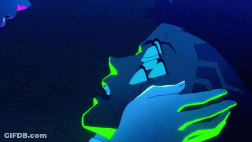 A Person With Neon Green Paint On Their Face Is Kissing Another Person In A Dark Room GIF