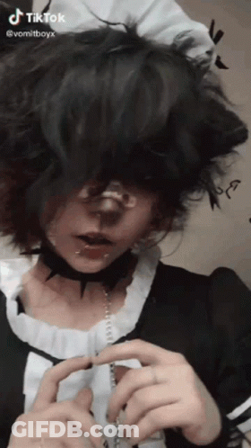 A Person With Short Black Hair And A Choker Around Their Neck Is Wearing A Maid Costume . GIF