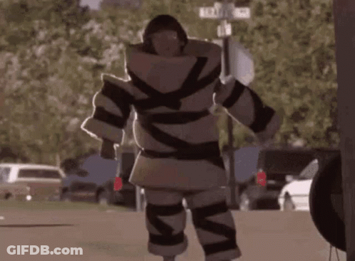 A Person Wrapped In Tape Is Standing On A Sidewalk . GIF