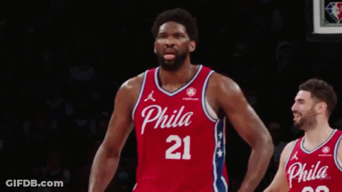 A Philadelphia Basketball Player Is Celebrating A Basket In Front Of A Crowd During A Game . GIF