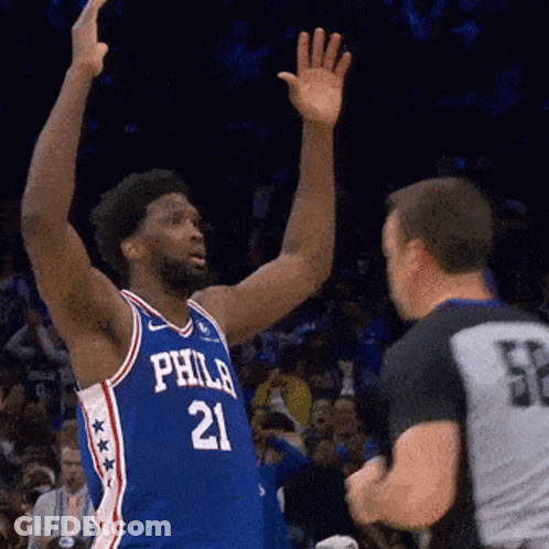 A Philadelphia Basketball Player Wearing Number 21 Reaches Up Towards A Referee GIF