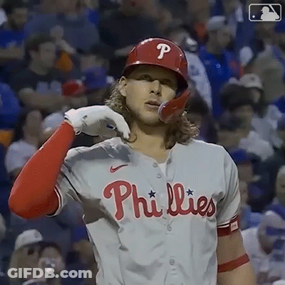 A Phillies Baseball Player Is Wearing A Red Helmet And A White Shirt . GIF