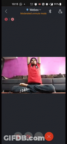 A Phone Screen Shows A Man Sitting In A Lotus Position With His Arms Up GIF
