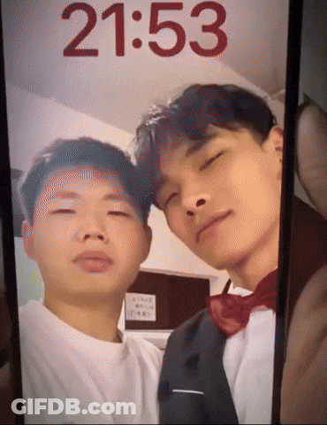 A Phone Screen Shows A Picture Of Two Men And The Time Is 2153 GIF