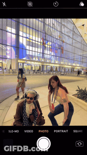 A Phone Screen Shows A Woman Taking A Picture Of A Man In Front Of A Building That Says Las Vegas GIF