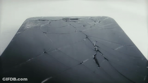 A Phone With A Cracked Screen Is Sitting On A White Surface GIF