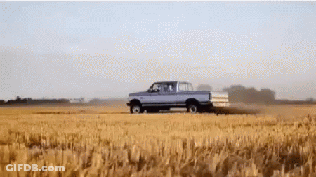 A Pickup Truck Is Driving Through A Wheat Field GIF