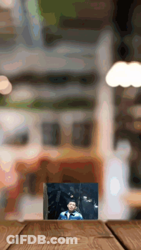 A Picture Of A Boy In A Graduation Cap And Gown On A Wooden Table GIF