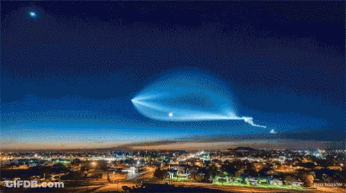 A Picture Of A City At Night With A Blue Sky And A Star In The Background GIF