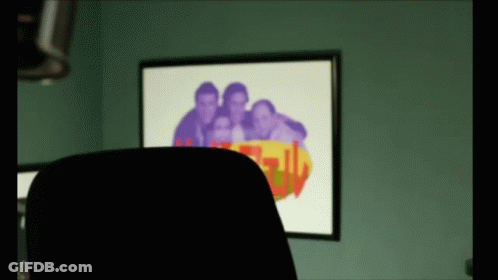 A Picture Of A Group Of People Is Behind A Chair In Front Of A Wall With A Picture On It GIF