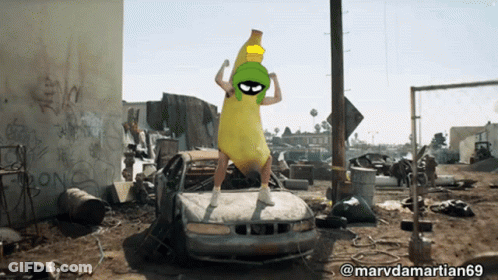 A Picture Of A Man Dressed As Marvin The Martian Standing On A Car GIF