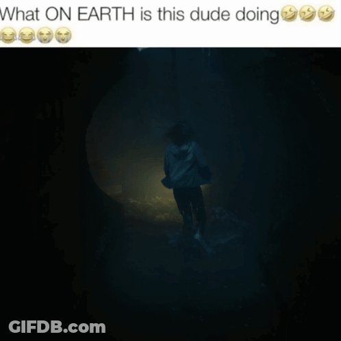 A Picture Of A Man Holding A Flashlight In A Dark Room With The Caption What On Earth Is This Dude Doing GIF