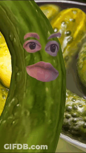 A Picture Of A Pickle With A Face On It And A Bowl Of Pickles In The Background GIF