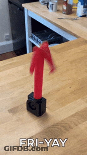 A Picture Of A Red Arrow On A Wooden Table With The Caption Fri-Yay GIF