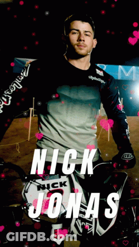 A Picture Of Nick Jonas With A Motorcycle In The Background GIF