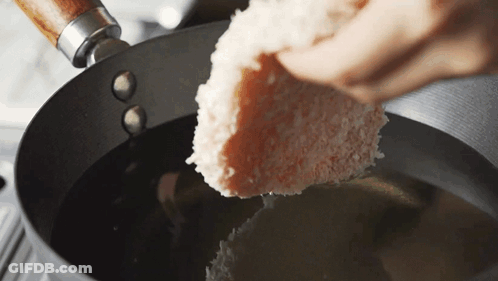 A Piece Of Bread Is Being Poured Into A Pan Of Oil GIF
