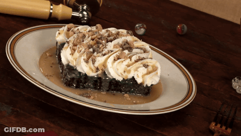 A Piece Of Cake With Whipped Cream And Caramel Sauce On A White Plate GIF