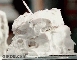 A Piece Of Cake With White Frosting And A Candle On Top GIF