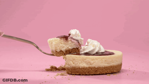A Piece Of Cheesecake With Whipped Cream On Top Is Being Eaten With A Fork GIF