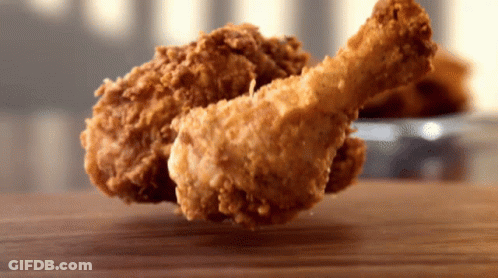 A Piece Of Fried Chicken Is On A Wooden Table GIF