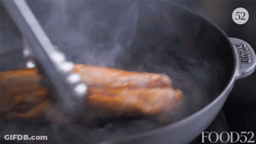 A Piece Of Meat Is Being Cooked In A Pan With The Number 52 On It GIF