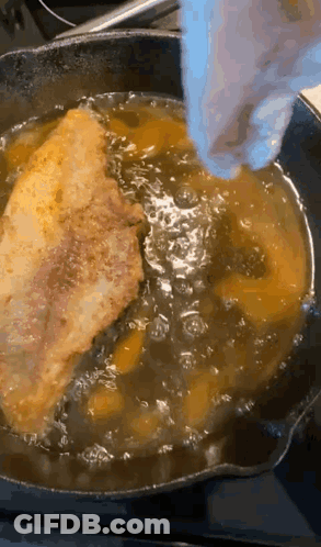A Piece Of Meat Is Being Cooked In A Skillet With Oil GIF