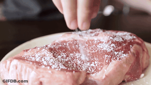 A Piece Of Raw Meat Is Being Seasoned With Salt GIF
