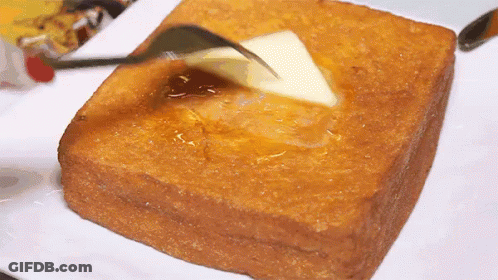 A Piece Of Toast Is Being Buttered With A Fork . GIF