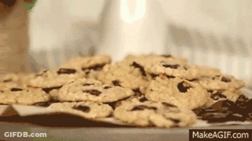 A Pile Of Chocolate Chip Cookies On A Table With Makeagif.com Written On The Bottom Right GIF