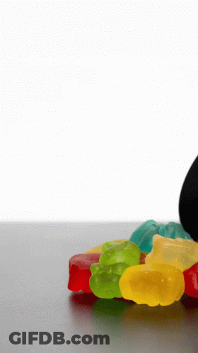 A Pile Of Colorful Gummy Bears On A Table With A White Background GIF