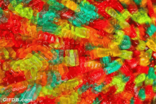 A Pile Of Colorful Gummy Bears With A Green One In The Middle GIF