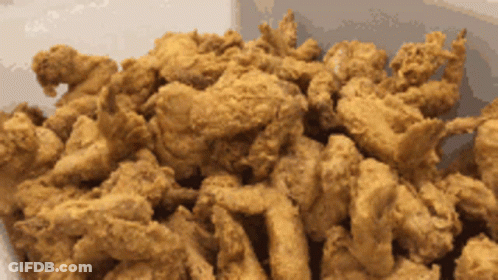 A Pile Of Fried Chicken Is Sitting On A White Surface GIF