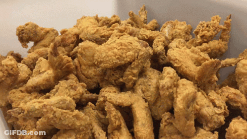 A Pile Of Fried Chicken Pieces In A White Container GIF
