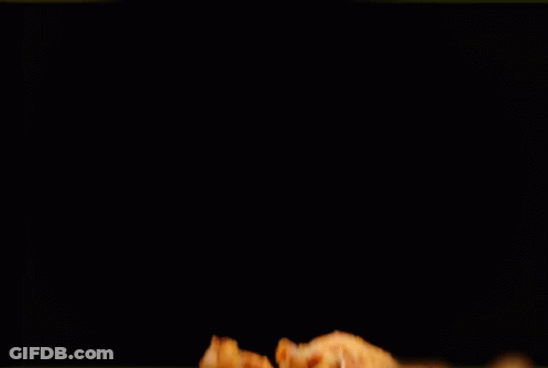 A Pile Of Fried Chicken Wings On A Black Table GIF