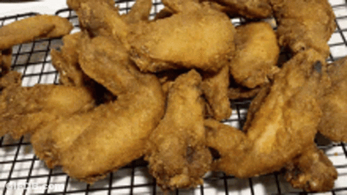 A Pile Of Fried Chicken Wings On A Wire Rack GIF