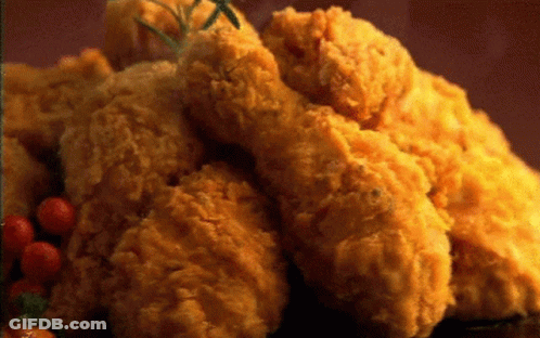 A Pile Of Fried Chicken With Tomatoes And Rosemary On A Table GIF