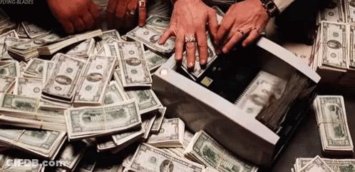 A Pile Of Money Is Sitting On A Table And A Person Is Taking Money Out Of A Box . GIF