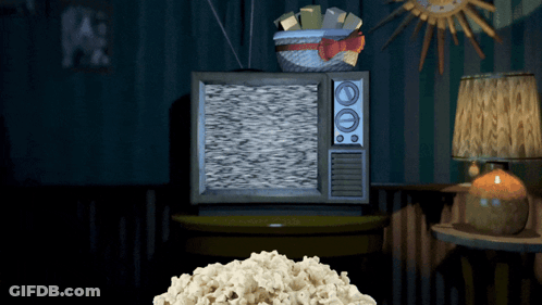 A Pile Of Popcorn Sits On A Table In Front Of An Old Fashioned Television GIF