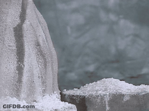 A Pile Of Snow Is Sitting Next To A Rock GIF