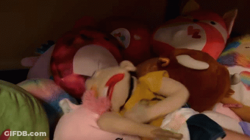 A Pile Of Stuffed Animals Including A Stuffed Animal With A Heart On Its Face GIF