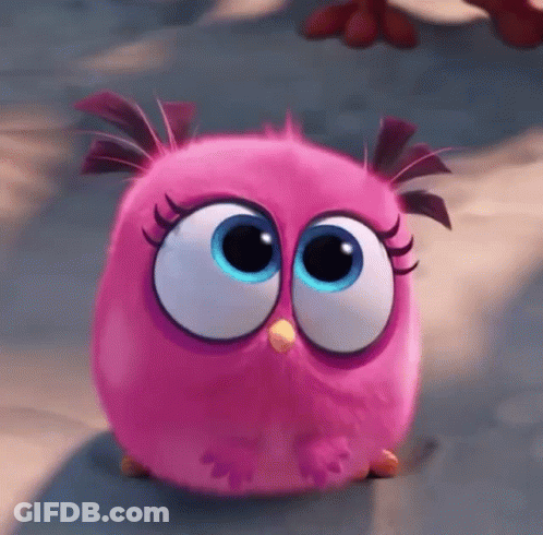A Pink Angry Bird With Big Blue Eyes Is Sitting On The Ground GIF
