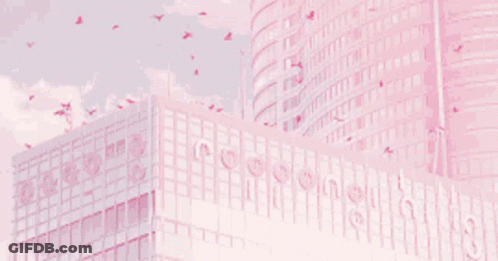 A Pink Building With Birds Flying Around It GIF