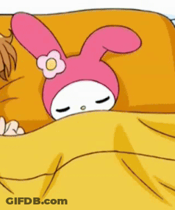 A Pink Bunny With A Flower On Its Head Is Laying On A Bed With A Yellow Blanket . GIF